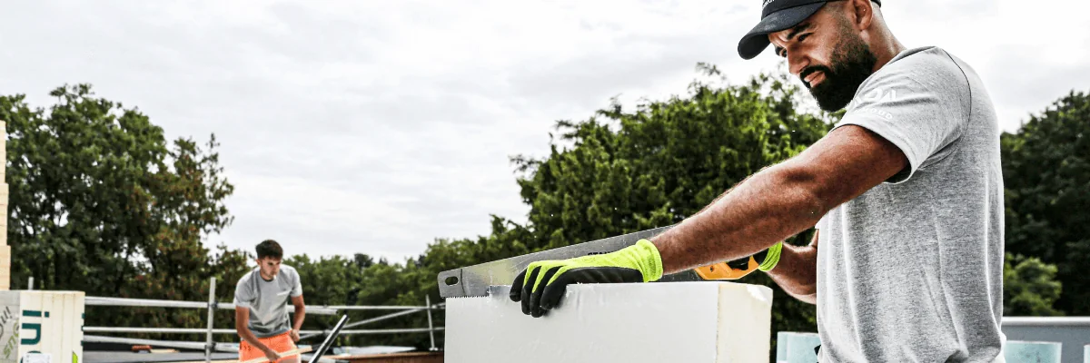 Dakdekker bezig met het zagen van plat dak isolatie