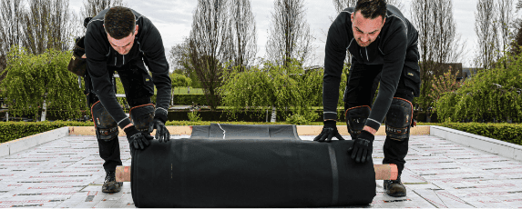 EPDM dakbedekking uitrollen Twee dakdekkers die EPDM dakbedekking aan het uitrollen zijn op een plat dak