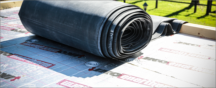 Twee dakdekkers rollen EPDM dakbedekking uit bovenop verlijmde IKO Enertherm isolatie – perfecte combinatie van A-keus isolatie en hoogwaardige dakafdichting.