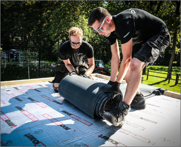Twee dakdekkers rollen EPDM dakbedekking uit bovenop verlijmde IKO Enertherm isolatie – perfecte combinatie van A-keus isolatie en hoogwaardige dakafdichting.